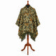 Sage and rust camo alpaca wool poncho – front view on a wooden mannequin stand: hooded poncho in pale sage green with rust-brown and black camouflage and deep olive fringe