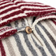 Button and cord loop at the neckline of the striped llama wool poncho