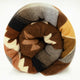 A rolled-up blanket with geometric and zigzag patterns in shades of brown, gray, and yellow rests on a plain white background.