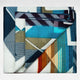 A folded blanket with a geometric, multicolored pattern in shades of blue, orange, and brown, resting against a plain white background.