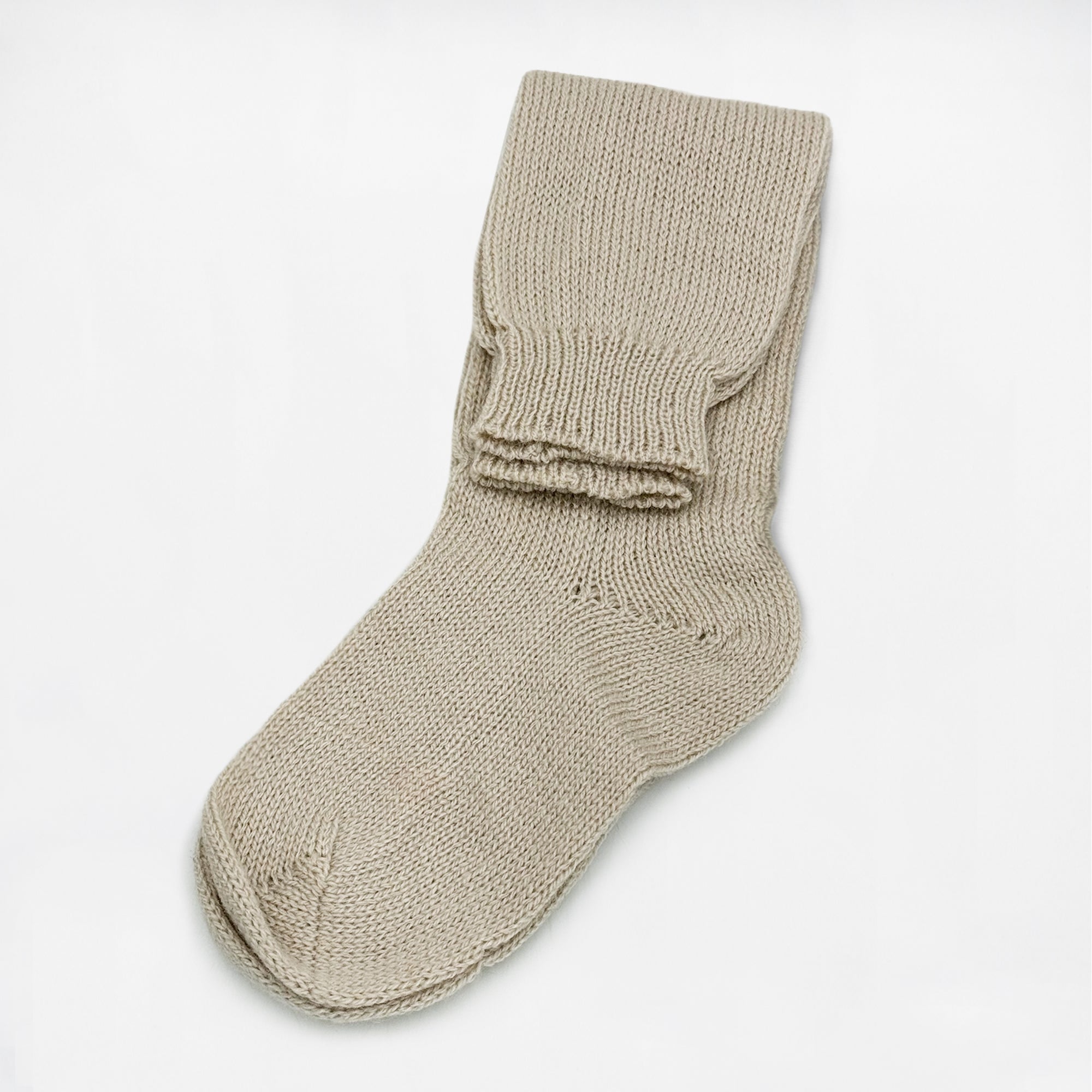 Beige knitted sock lies flat with its cuff folded at the top, placed against a plain white background.