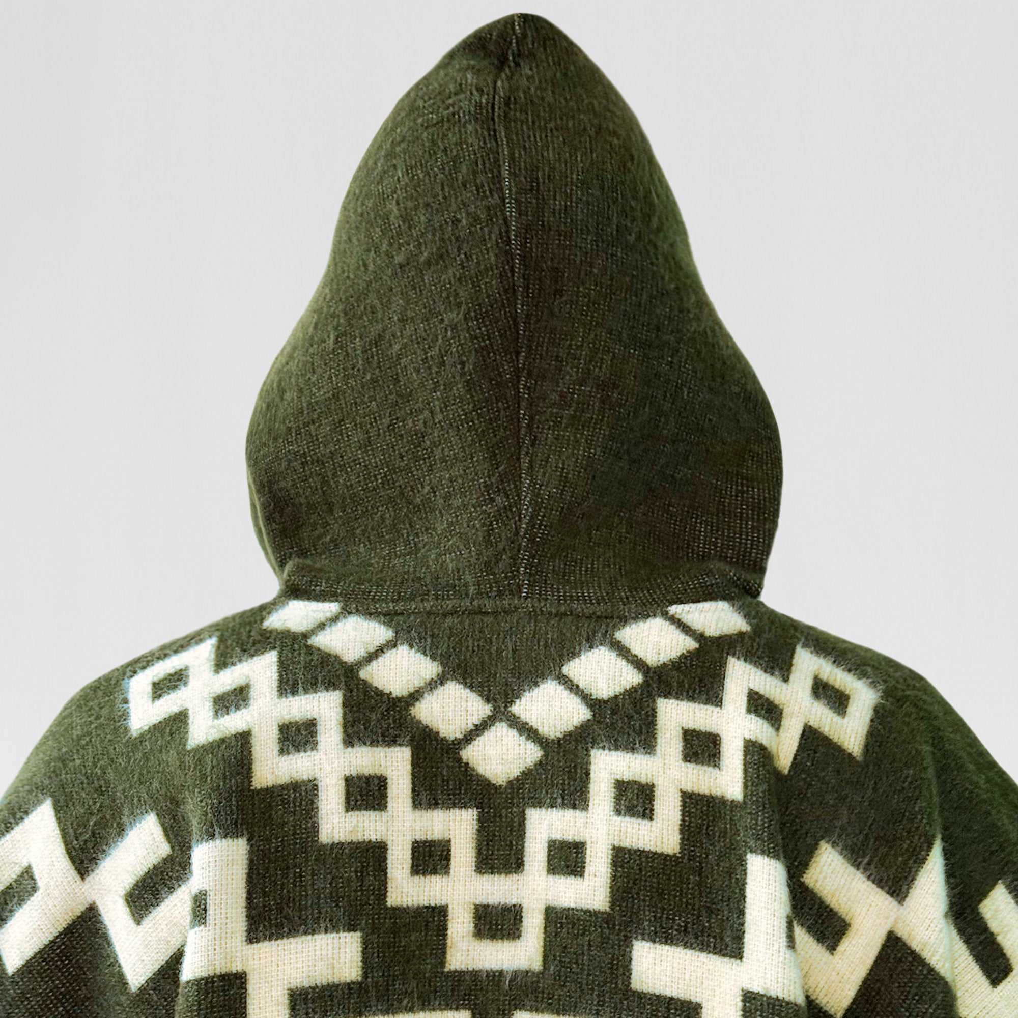 A dark green hooded garment with intricate white geometric patterns is displayed against a plain background, highlighting the design on the back.