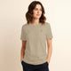 Woman wearing a beige t-shirt with an logo on a beige background