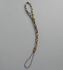 A braided strap forms a loop, featuring intertwined gold, brown, and white threads against a plain gray background.