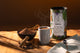 Hot cacao drink with steam, wooden bowl of cacao powder and cinnamon sticks