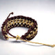A woven bracelet made of brown and beige strands forms a circular pattern with an adjustable knot, laid on a plain white surface.