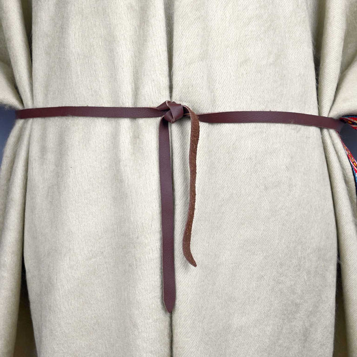 A beige fabric garment is tied with a narrow brown belt, knotted at the front, seen against a gray background.