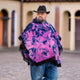 A person wearing a black hat and a vibrant pink and blue poncho stands in a cobblestone plaza, with blurred arches in the background.
