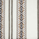 A woven fabric displays intricate, symmetrical diamond patterns in brown, black, and white stripes, set against a cream background, evoking a traditional or ethnic textile appearance.