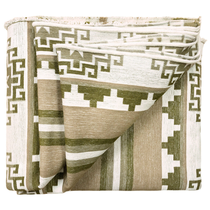A woven blanket, folded neatly, features a green and beige geometric pattern with stripes and angular designs, placed on a white background.