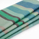 Sucua baby alpaca wool blanket – a folded woolen blanket with green, blue, and gray striped patterns lies on a plain white surface