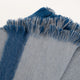 A blue and gray woolen blanket is spread out, displaying soft, fringed edges, on a neutral surface, conveying warmth and comfort.