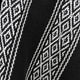 A fabric strap features white diamond and zigzag patterns on a black knitted background, showcasing intricate woven details in close-up view.