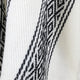 Textile features black geometric patterns woven into a white fabric, showcasing diamond shapes and intricate lines, creating a visually striking contrast with the soft, textured background.