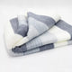Cayambe baby alpaca wool blanket – a folded, striped blanket with gray and white horizontal bands, resting on a plain white surface, creating a soft and cozy appearance