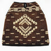 A brown woolen poncho features cream geometric patterns, including a central diamond design and horizontal lines, placed on a flat surface.