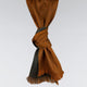 A brown and dark grey woven scarf, featuring a knotted section in the center, hangs against a plain grey background. The scarf has fringed ends, adding texture to its appearance.