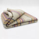 Quijos alpaca wool blanket – a folded woolen blanket displays purple, yellow, and gray stripes. It rests on a white surface in a neatly arranged fashion, emphasizing its soft, thick texture