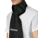 A textured dark scarf with a patterned pocket is wrapped around a person's neck, who is wearing a white shirt. The background is plain, highlighting the scarf's design.