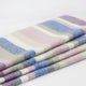Yunga baby alpaca wool blanket – a neatly folded soft woolen blanket features pastel stripes in blue, pink, gray, and cream, resting against a plain white background