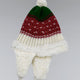 A knitted winter hat features red, green, and white colors with a pom-pom on top and earflaps. It's decorated with small white patterns, set against a plain background.