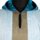 Hooded garment with a teal collar, featuring a vertical brown stripe and a button closure, surrounded by a light blue fabric, displayed on a black mannequin.