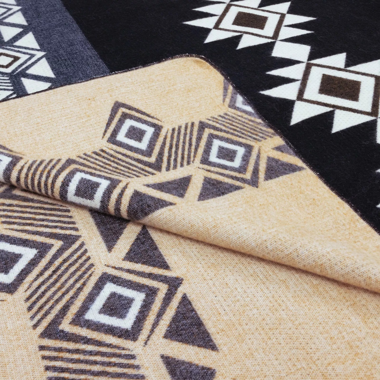 Fabric with geometric patterns lies folded. It features beige and black tones with white, square and star-like designs, set against contrasting backgrounds, creating an intricate, symmetrical appearance.