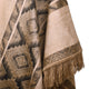 A fringed textile features intricate geometric patterns in earthy tones, creating a warm, textured aesthetic with overlapping diamond shapes in a woven fabric.