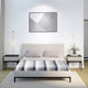 Cayambe baby alpaca wool blanket – a bed with a striped blanket and two pillows is centered between modern nightstands in a minimalist bedroom. Abstract art and decorative lights enhance the serene, stylish atmosphere