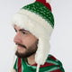 A person wears a festive red, green, and white knit hat with ear flaps, facing left, in a plain environment. The hat features a pom-pom and fluffy lining.