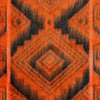 A close-up of an orange and black woven fabric displaying a geometric pattern with overlapping diamond shapes, creating a striking, symmetrical design. The texture appears soft and fuzzy.