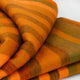 Putumayo baby alpaca wool blanket – a soft, folded blanket shows orange and brown stripes, resting on a light surface