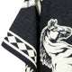 A black fabric features a white horse illustration, with geometric patterns along the edge, likely part of a garment or textile.