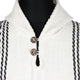 A white knitted garment with a collar features two brown buttons, with black stripes running vertically along the sides, against a plain white background.