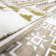 A woolen blanket is layered and partially folded, displaying geometric patterns in earth tones, including olive green and beige, set on a textured surface.