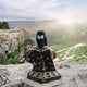 Kids Clint Eastwood alpaca wool poncho – a person wearing a patterned poncho sits on a cliff, overlooking a vast, sunlit valley with rolling green hills under a partly cloudy sky
