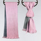 Scarves draped on hangers; one hangs down with pink and gray colors, while the other is knotted, showcasing a similar pink and gray pattern. The background is plain.