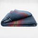 Huasaga baby alpaca wool blanket – a folded, multicolored blanket with blue, red, and yellow stripes rests on a plain, white background