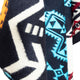 A textured fabric features vibrant geometric patterns in black, white, blue, orange, and red, creating an abstract, tribal-inspired design with zigzag and triangular motifs.