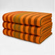 Putumayo baby alpaca wool blanket – three folded blankets display horizontal orange and brown stripes, stacked neatly against a plain, light-colored background