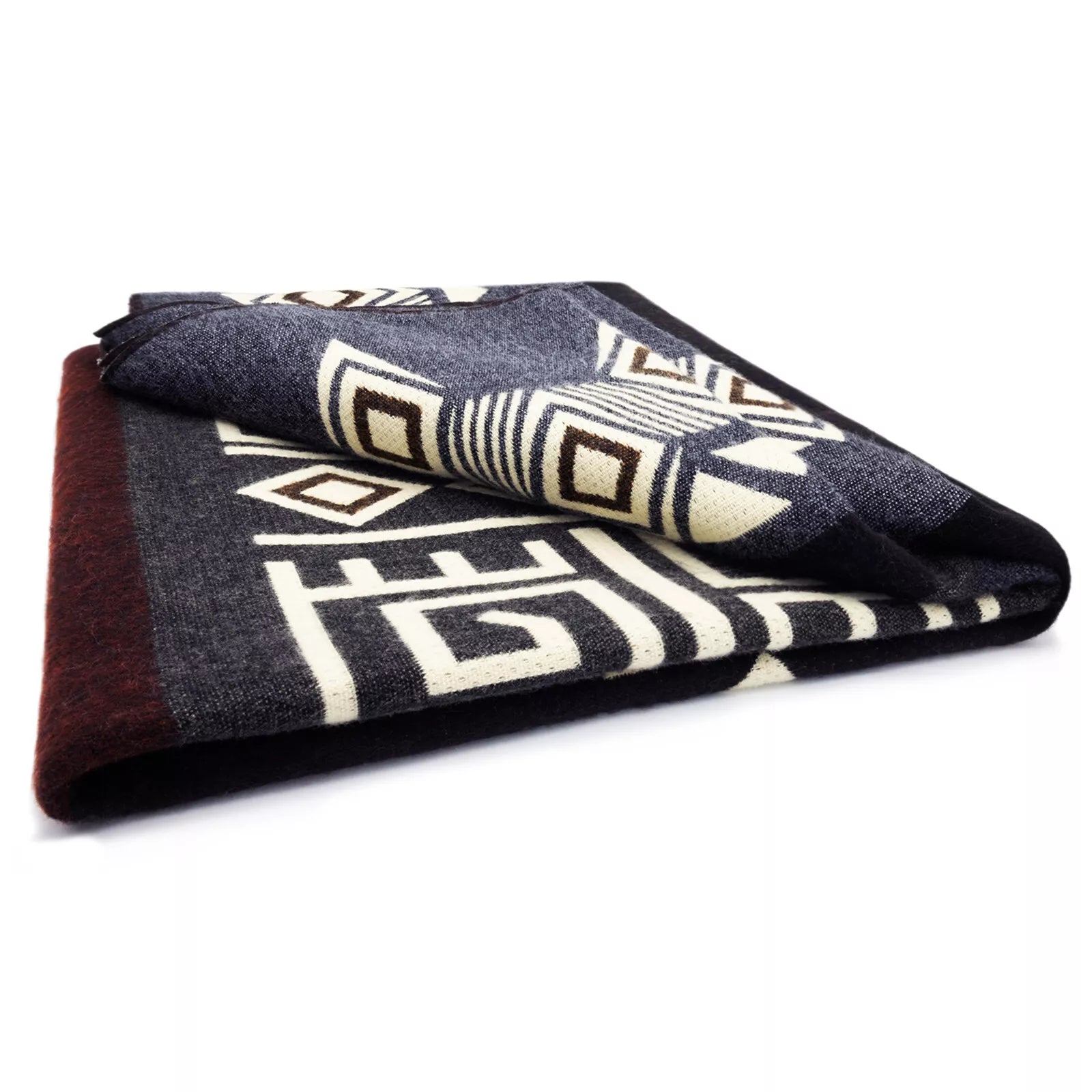 A folded textile features geometric patterns in white, brown, and gray colors. Resting on a white surface, its design includes diamond shapes and lines, suggesting a decorative or cultural theme.