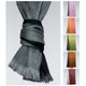 A grey scarf with fringed edges is knotted; adjacent are five scarf variations in different colors including pink, orange, green, brown, and maroon, all on a plain background.