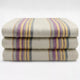Quijos alpaca wool blanket – three folded blankets, featuring multicolored stripes in purple and yellow, are stacked neatly on a plain white surface
