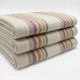 Quijos alpaca wool blanket – three folded woolen blankets with yellow, purple, and gray stripes stacked neatly against a plain white background