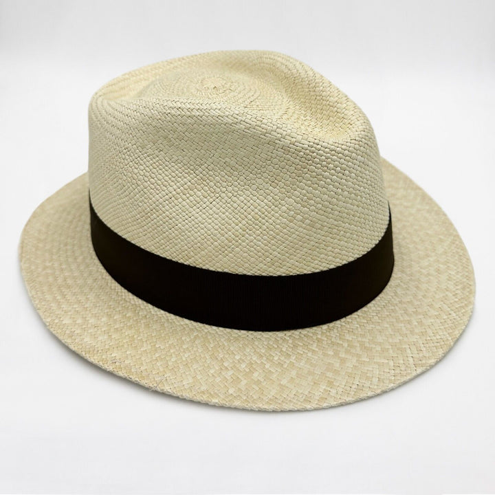 A beige woven fedora features a wide black band around the crown, set against a plain white background.
