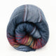 Huasaga baby alpaca wool blanket – a rolled-up blanket with a plaid pattern of blue, red, and gray hues rests on a white background, showing its soft texture and multicolored stripes