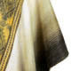 A close-up of a thick, soft woolen fabric showing a gradient from yellow to dark brown, with a hint of an intricate pattern, draped smoothly.