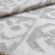 A soft, folded blanket with a blurred geometric pattern in light gray and white, resting on a flat surface.