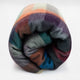 Anzu baby alpaca wool blanket – a rolled-up, multicolored plaid blanket featuring hues of purple, orange, green, and blue, set against a plain white background