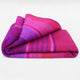Chone baby alpaca wool blanket – a folded, multi-colored wool blanket with pink, purple, and red stripes rests on a plain white background, showcasing its vibrant, rich textures and patterns
